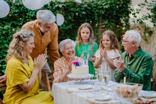 An elderly lady having a birthday party with her family and a live-in carer.