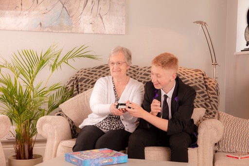 Client laughing whilst her grandson teaches her how to play video games