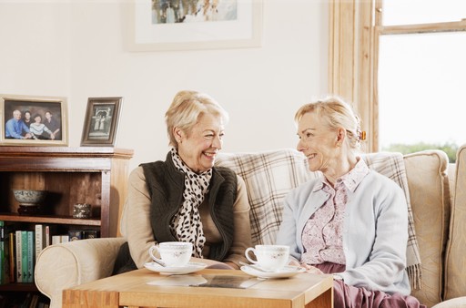 Nurse and client laughing together while sat in the client's living room