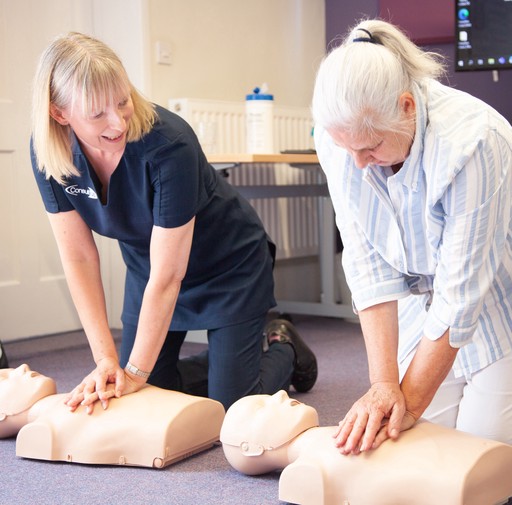 Susan supporting a carer learning to perform CPR
