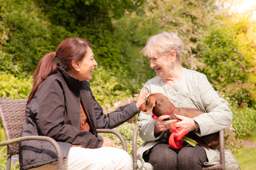 Carer and client sat in a sunny garden with the client's dog